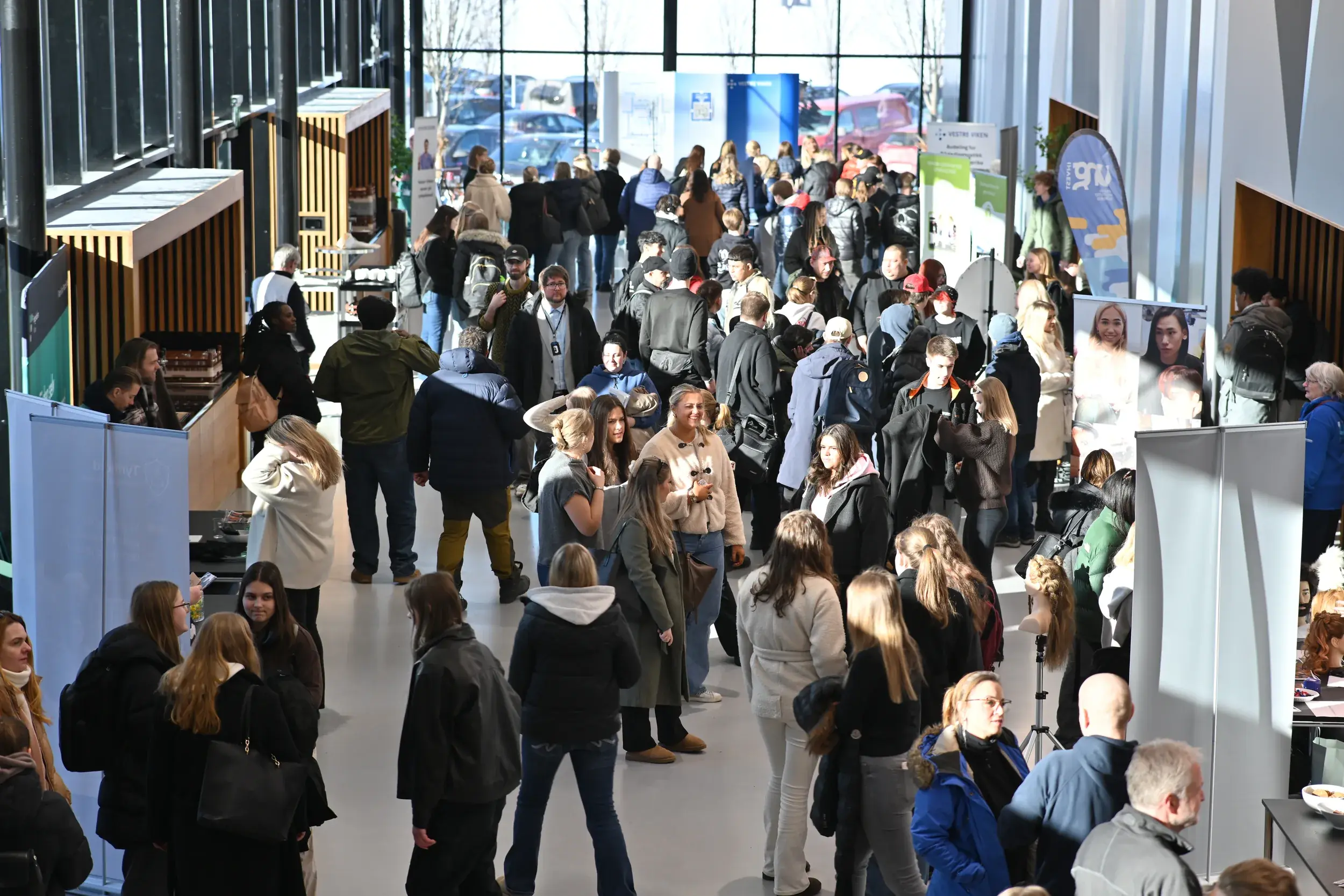 Besøkende og utstillere i den lyse foajeen